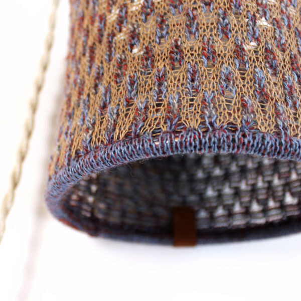 Détail d'une lampe d'appoint baladeuse à suspendre en maille, tricot de laine. Suspension design artisanale et fait main.