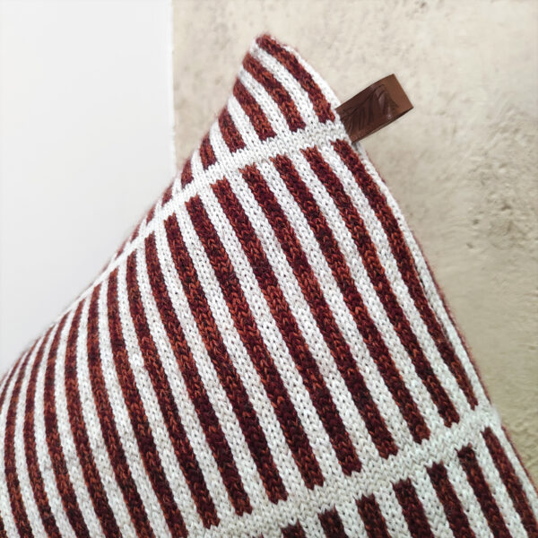 Détail d'un coussin berlingot rayé en maille tricotée. Coussin de décoration design original et géométrique, rembourré en pure laine bretonne