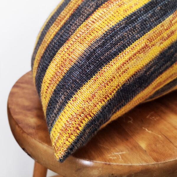 Détail d'un coussin berlingot à rayures en maille tricotée. Coussin de décoration design original et géométrique, rembourré en pure laine bretonne